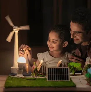 Girl and teacher testing a model wind turbine and solar panel